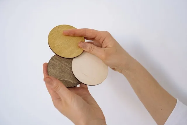 hands holding three wood coasters for how to make wooden coasters waterproof
