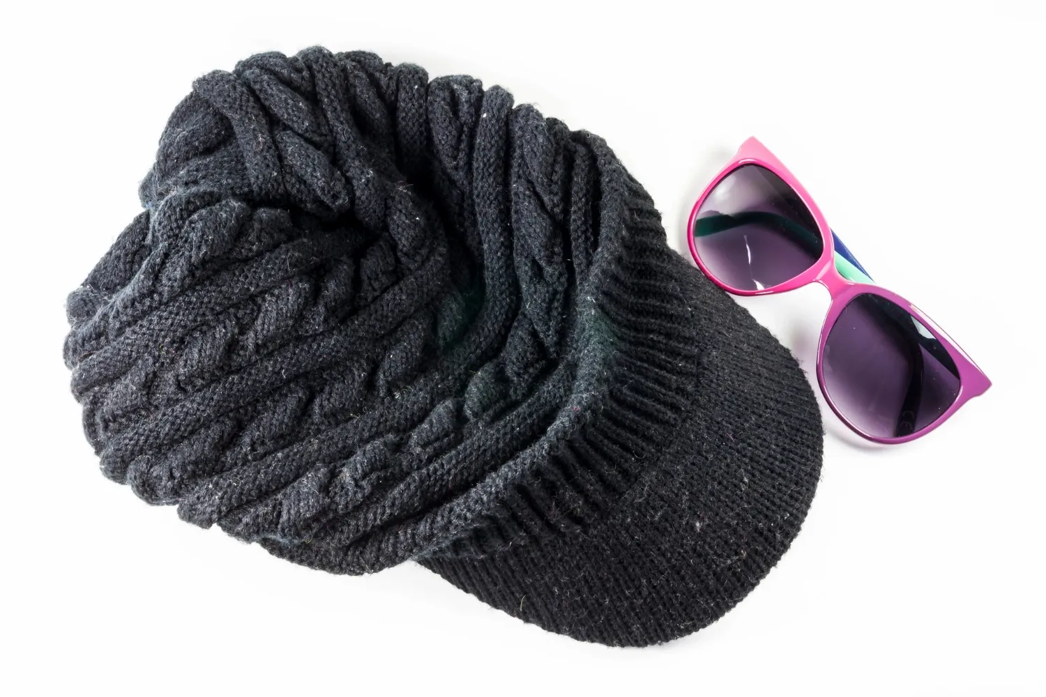 Black knitting wool hats and sunglasses on white