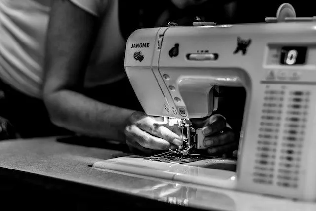 Black and white photo of person using sewing machine for how to make custom embroidered patches