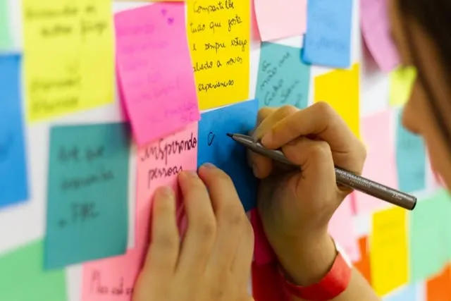 a person writing on sticky notes for who invented post-it notes