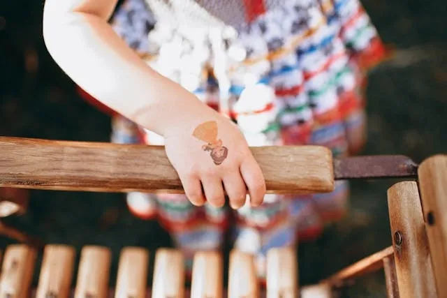 a child’s hand with a tattoo sticker for how to remove temporary tattoos