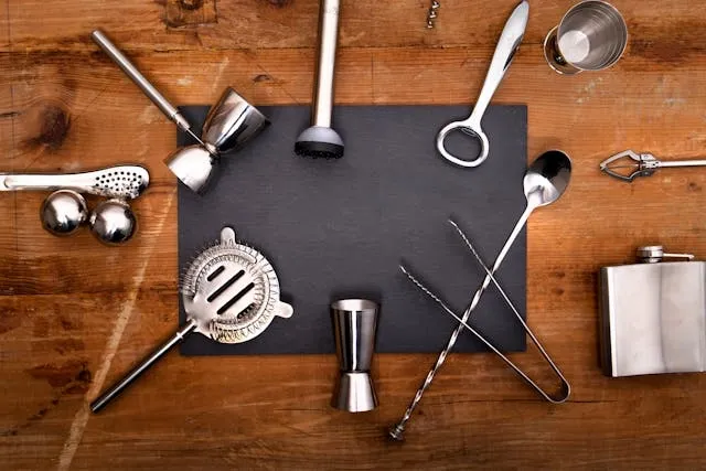 a selection of bar tools on a wooden surface for how to measure a shot without a shot glass