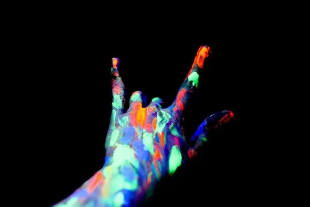 a hand covered in fluorescent paint for do neon colors glow under black light