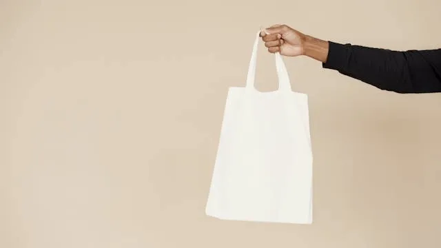 a person holding a beige tote bag for how to store reusable shopping bags