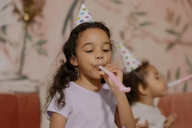a child wearing a party hat and blowing a party horn for birthday party essentials