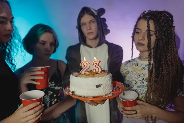 young adults holding a birthday cake for birthday party essentials