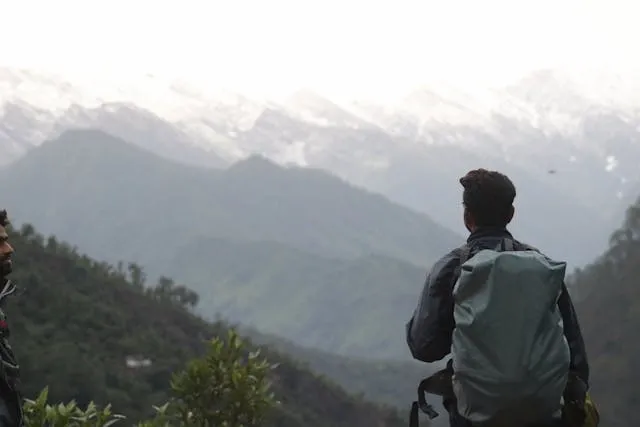 a person with a gray backpack looking at a mountain for how to measure torso for backpack