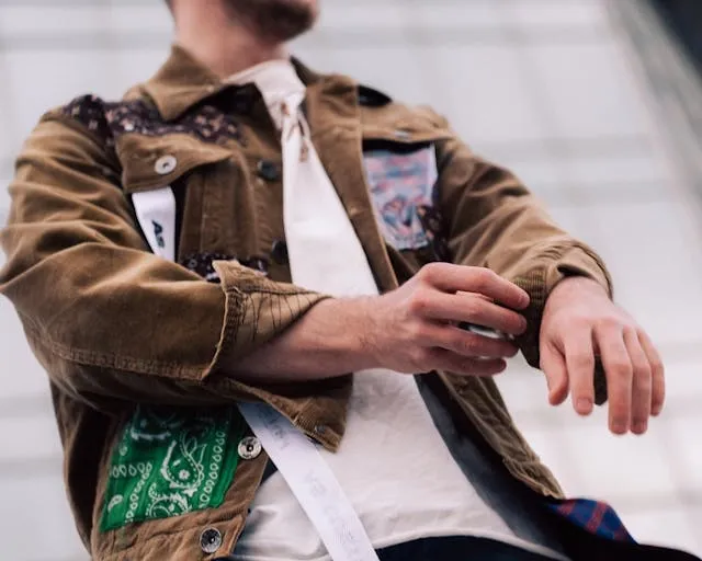 a person wearing a brown jacket with colorful patches for how to remove an embroidered patch from a jacket