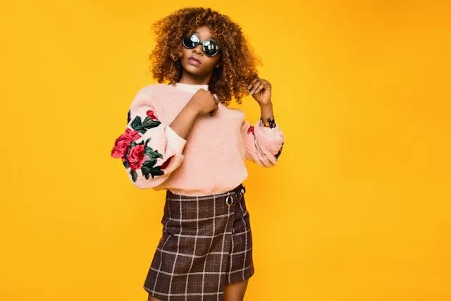 a stylish person in a pink sweatshirt and brown plaid skirt for gifts for fashion lovers