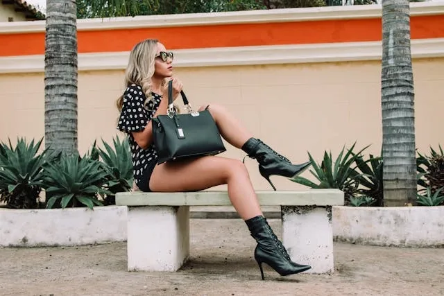 a person wearing black and white polka dots holding a leather bag on a white concrete bench for gifts for fashion lovers