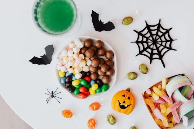 assorted candies and decorations on a white table for halloween table top decor