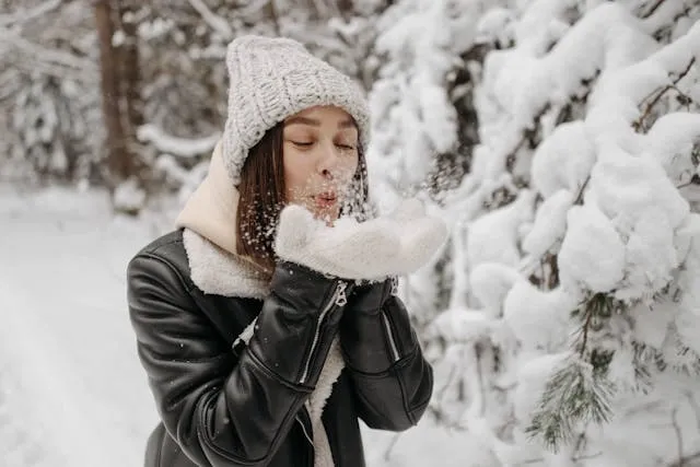 a person in black leather blowing snow from their hands for how to style a moto jacket