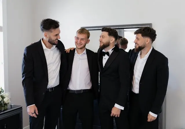 four people smiling in tuxedos for bachelor party decorations