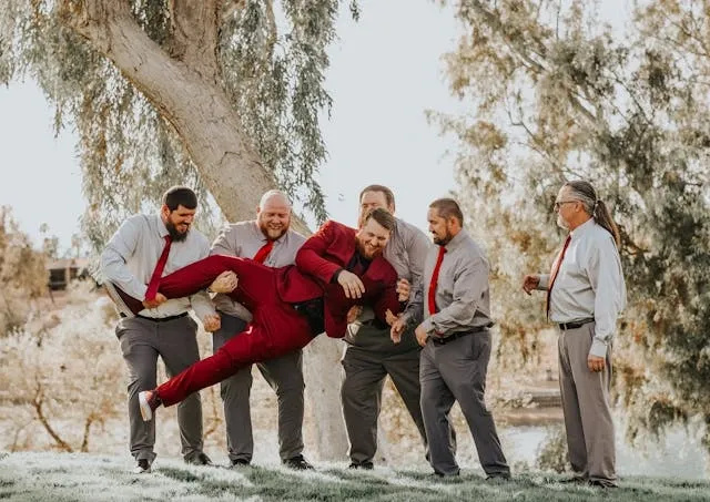 a group of people holding a man in a red suit for bachelor party decorations
