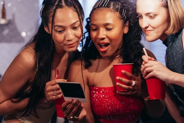 people looking at an instant photo at a party for engagement party ideas at home