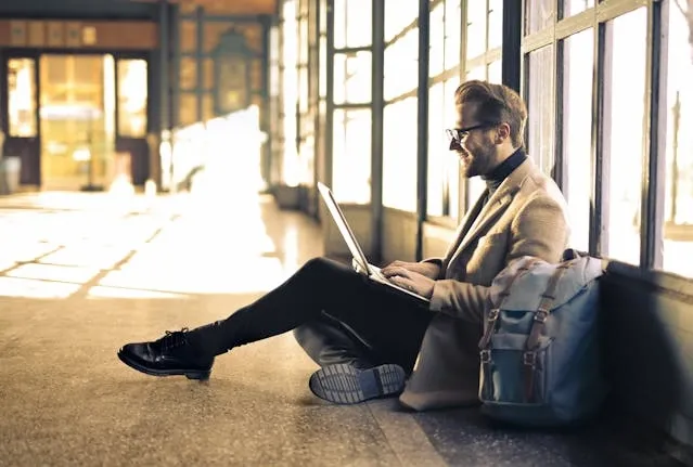 a person sitting on the floor with a laptop for types of backpacks