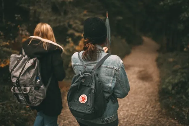 two people walking on a forest path for how to measure a backpack