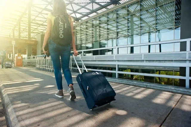 a person carrying luggage on a walkway for how to wear a backpack