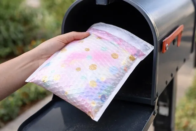 someone putting a mailer into a mailbox for bubble mailer sizes