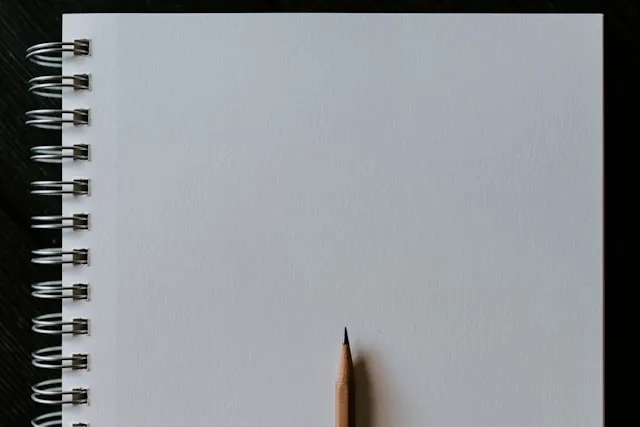 a pencil on an opened notebook for notebook sizes