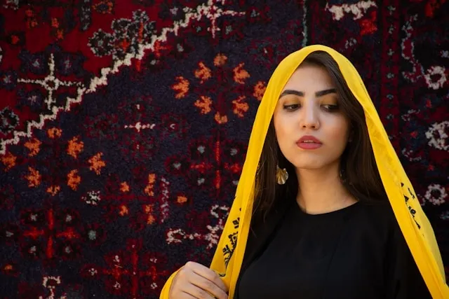 a person with a yellow shawl on their head for how to tie a scarf on your head