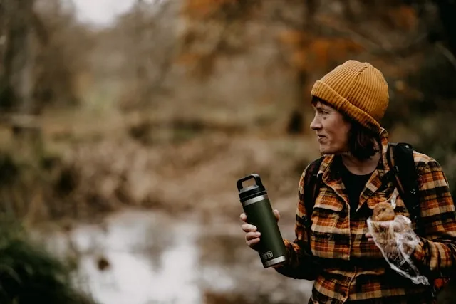 a person holding an insulated tumbler in the woods for best insulated tumbler