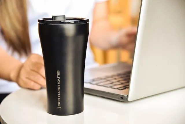 a black tumbler beside a laptop for what is a tumbler