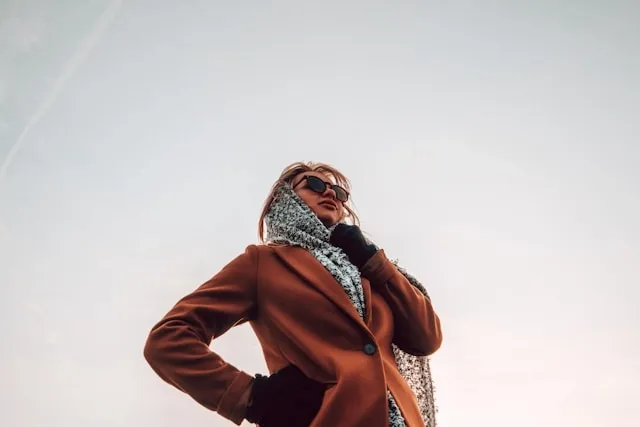 a low-angle view of a person wearing a shawl and coat for how to turn a scarf into a shawl