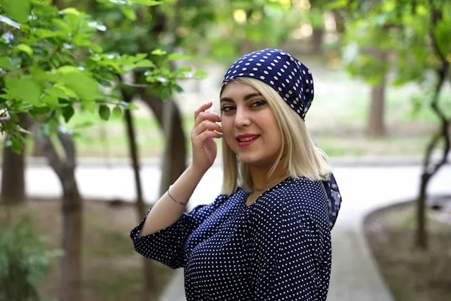 a person wearing a polka dot headscarf outdoors for how to wear silk scarf on head