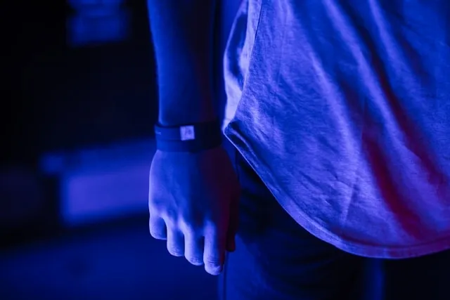 a person wearing wristbands under blacklight for how to take off festival wristband