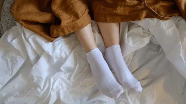 feet in socks sticking out from a blanket for does sleeping with socks affect the brain