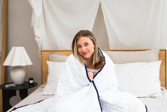 a person wrapped in a white blanket for how to wash a weighted blanket