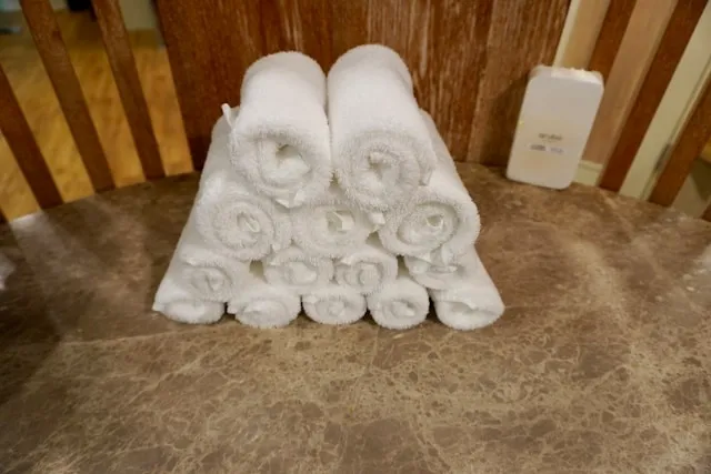 a pile of rolled white towels on the floor for how to wash towels