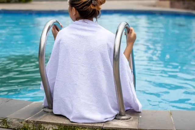 a person sitting by a pool in a white towel for how to whiten towels without bleach