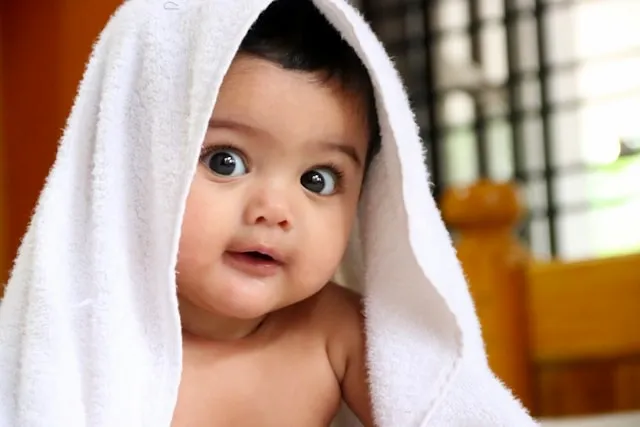 a baby with a white towel over its head for how to wash towels