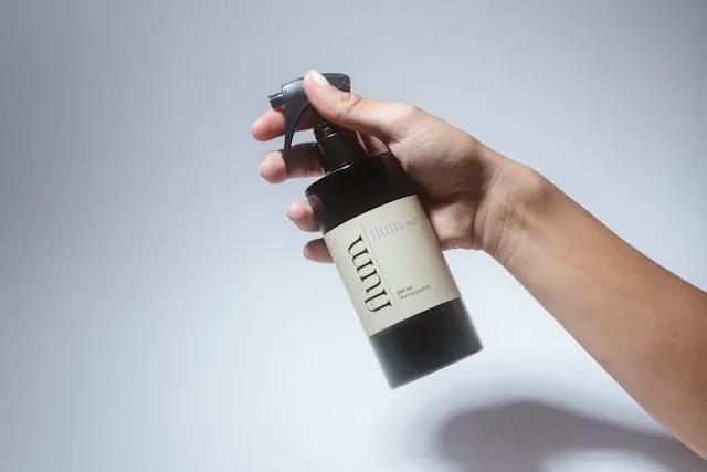 a person holding a freshener spray bottle for how to use room freshener