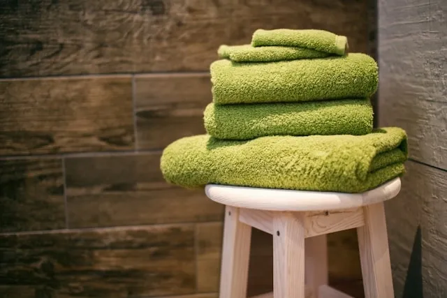 green towels piled in a bathroom for how to wash towels