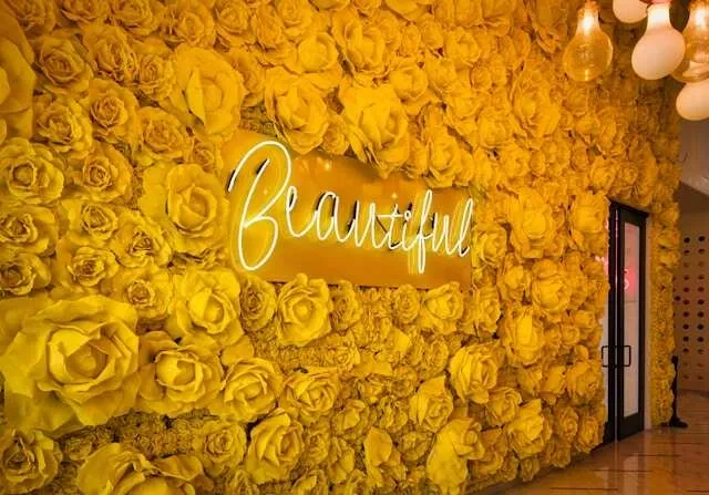 a yellow neon sign on a floral wall for how to fix neon sign