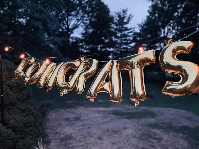 a hanging sign made from balloons for engagement party backdrop ideas