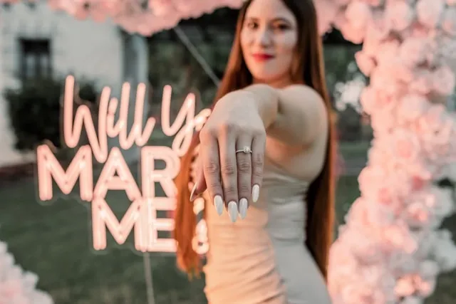 a person posing with an engagement ring for engagement party backdrop ideas