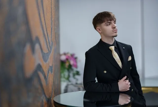 a person wearing a black suit for can you wear a lapel pin and pocket square