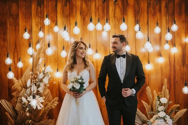 a couple stand in front of a wedding backdrop for wedding neon sign backdrop
