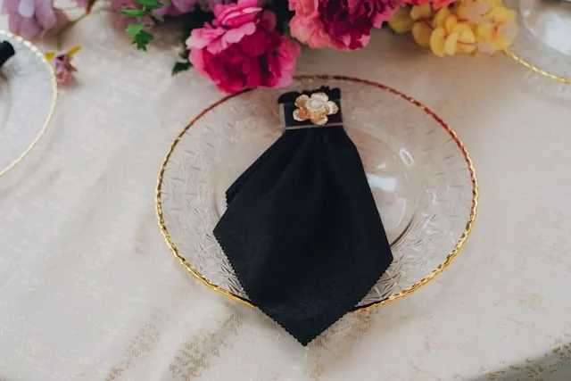 a black napkin folded on a plate for how to fold napkins with rings