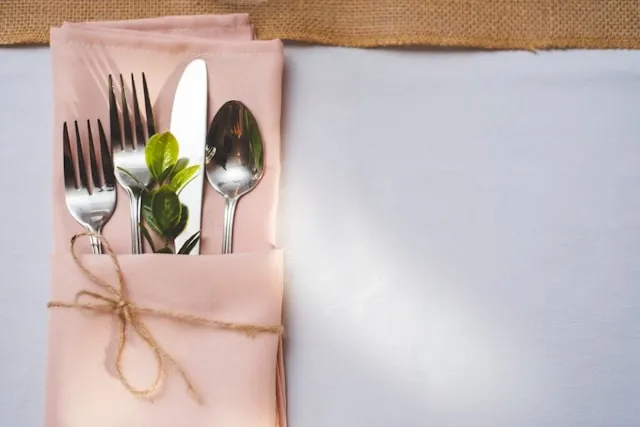 a pink napkin with silverware inside for how to wrap silverware in a napkin