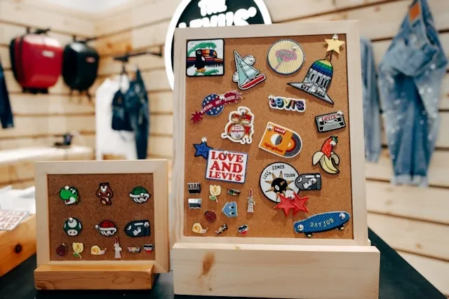 a collection of enamel pins on a cork board for hard vs soft enamel pins