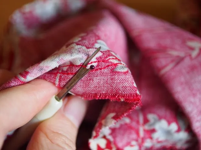 a person working on stitching on fabric for how to make a tablecloth