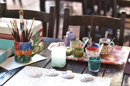 Hand-painting custom designs onto ceramic coaster blanks with brushes and colorful ink at a Cricut coaster crafting workstation Hand-painting custom designs onto ceramic coaster blanks with brushes and colorful ink at a Cricut coaster crafting workstation