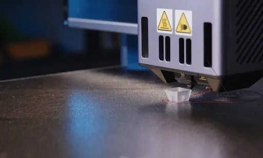 Laser engraver head with safety warning labels engraving a flat work surface during leather patch production