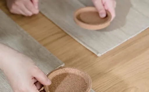 Hands preparing a blank coaster on a table before taping the sublimation transfer when learning how to sublimate a coaster Hands preparing a blank coaster on a table before taping the sublimation transfer when learning how to sublimate a coaster