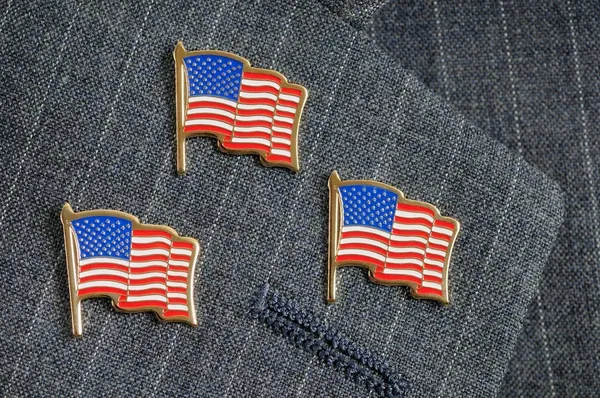 Three American flags pinned to a lapel Three American flags pinned to a lapel